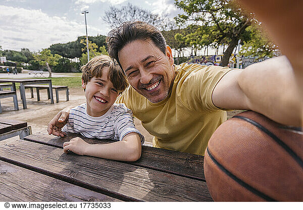 Cheerful man with son taking selfie on sunny day