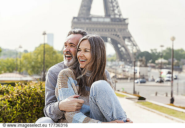 Cheerful mature couple sitting together in front of Eiffel tower  Paris  France