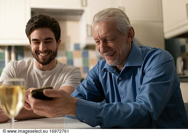 Cheerful mature father showing photos to son