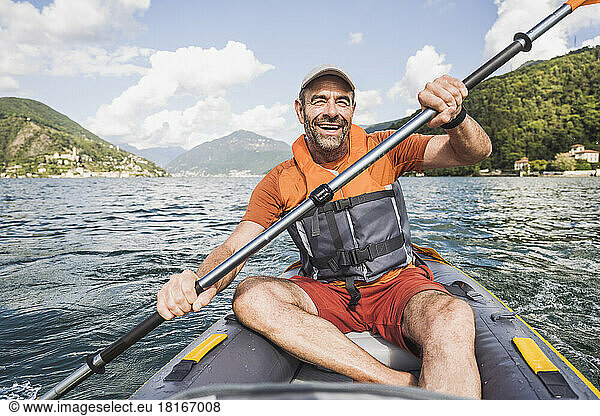 Cheerful mature man enjoying kayaking at lake