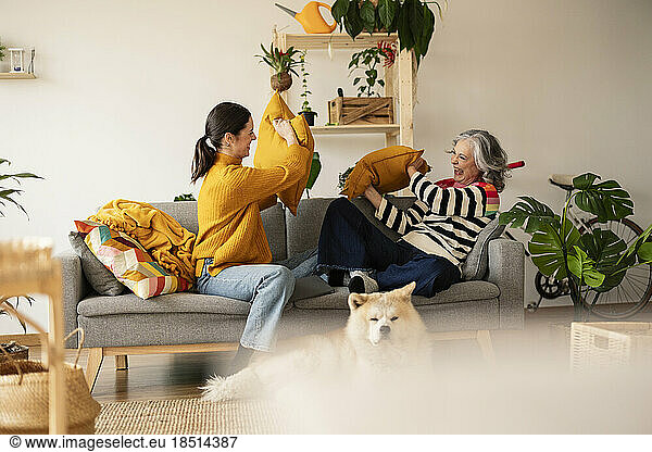 Cheerful mother and daughter enjoying pillow fight at home