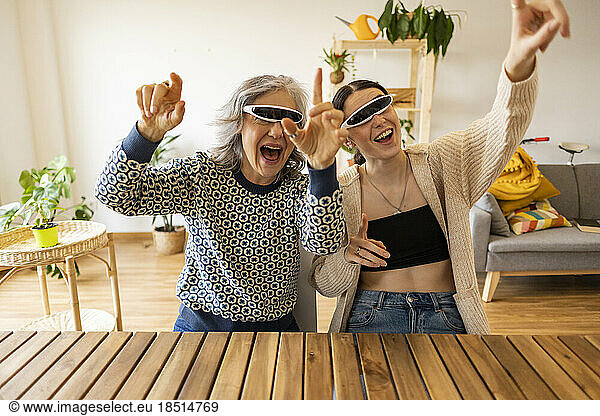 Cheerful mother and daughter wearing smart glasses having fun at home