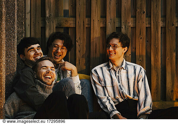 Cheerful multi-ethnic male friends spending leisure time in balcony