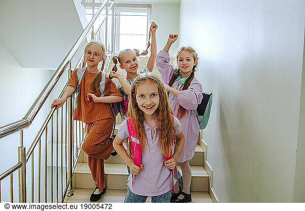 Cheerful schoolgirls standing on school staircase