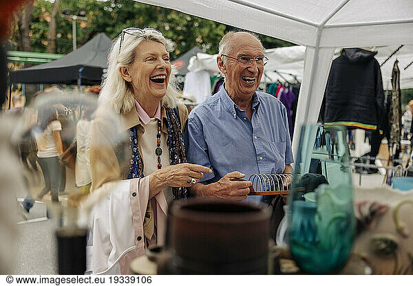 Cheerful senior couple shopping at market in city