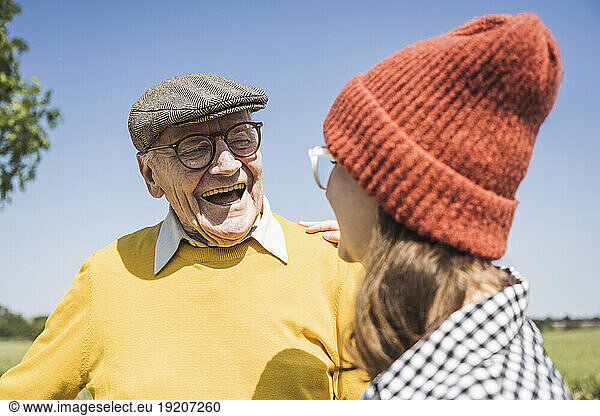 Cheerful senior man with granddaughter wearing knit hat