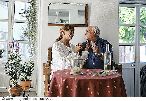 Cheerful senior woman and man sitting with wine glasses in cafe