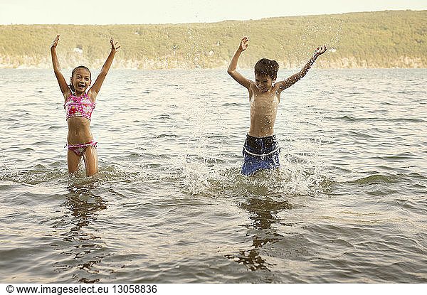 Cheerful siblings playing in lake