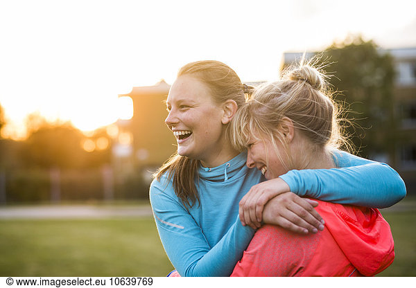 Cheerful sporty sisters embracing at park