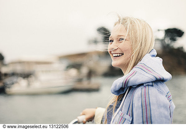 Cheerful teenage girl looking away by lake