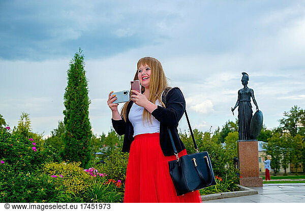 Cheerful tourist woman with down syndrome taking smartphone photo
