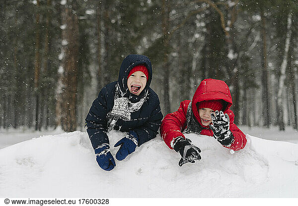 Cheerful twin brothers playing in snowy forest