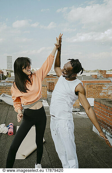 Cheerful woman giving high-five to male friend on rooftop