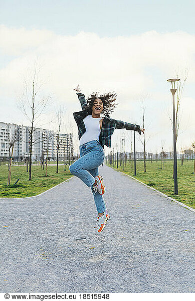 Cheerful woman jumping on footpath