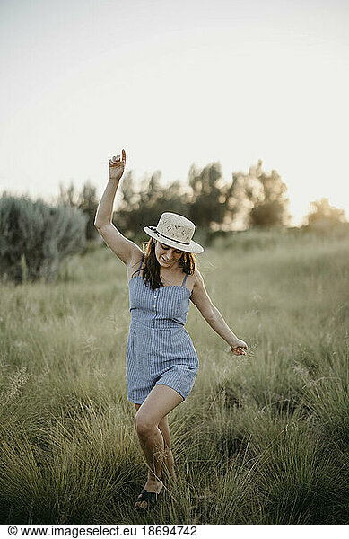 Cheerful woman running on meadow at sunset