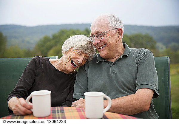 Cheerful woman sitting with husband at table in lawn