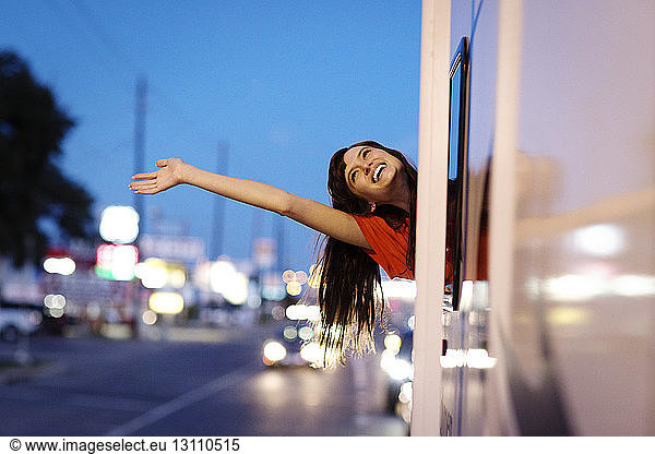 Cheerful woman waving while leaning out of camper van