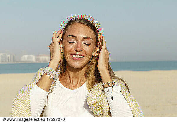 Cheerful woman with a birthday headband on the beach