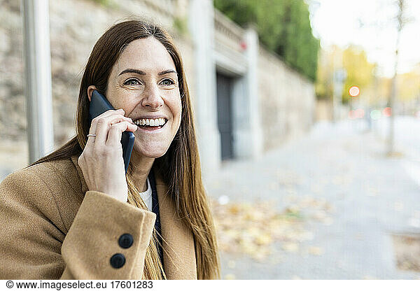 Cheerful woman with brown hair talking on smart phone