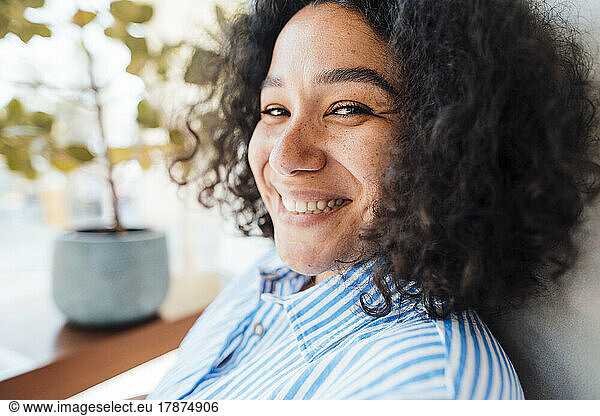 Cheerful woman with curly hair at cafe