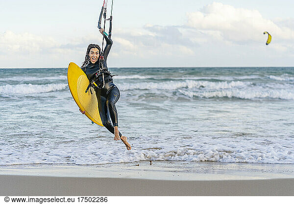 Cheerful woman with kiteboard surfing at beach