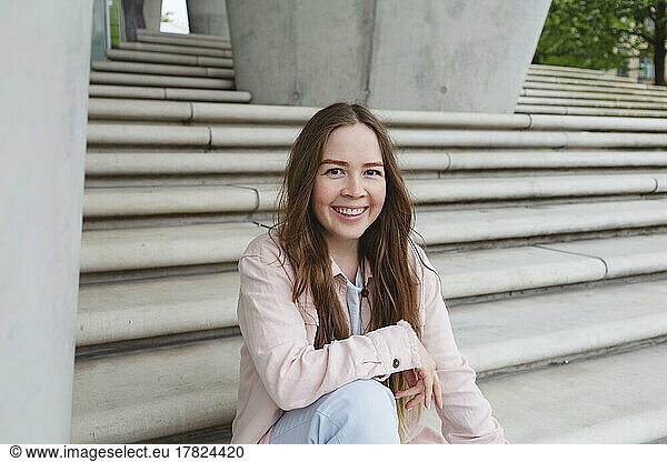 Cheerful woman with long hair sitting on steps