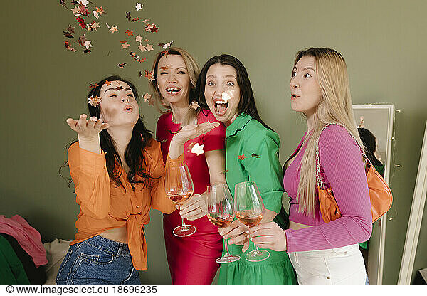 Cheerful women celebrating together holding wineglasses at home