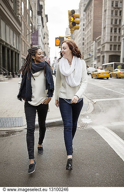 Cheerful women looking face to face while walking on street