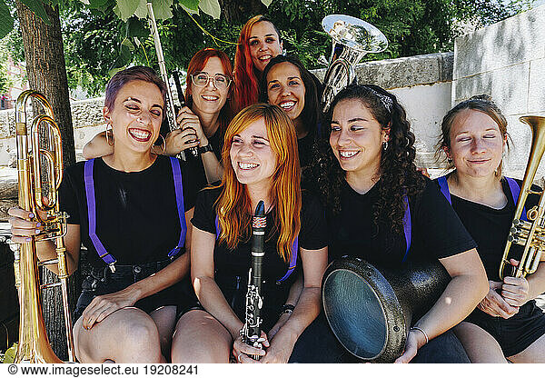 Cheerful women's folk music group sitting together holding wind instruments
