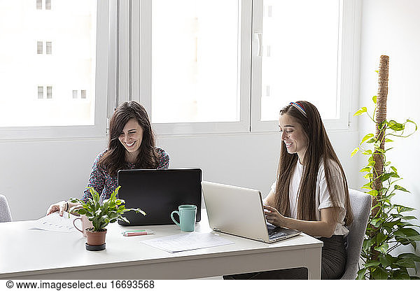 Cheerful women using laptops in office