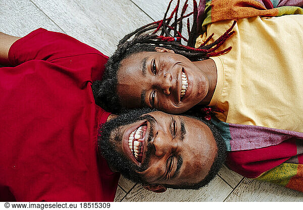 Cheerful young friends lying on floor at home