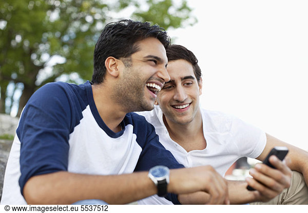 Cheerful young male friends sharing something in mobile phone