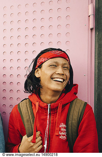 Cheerful young man looking away against wall