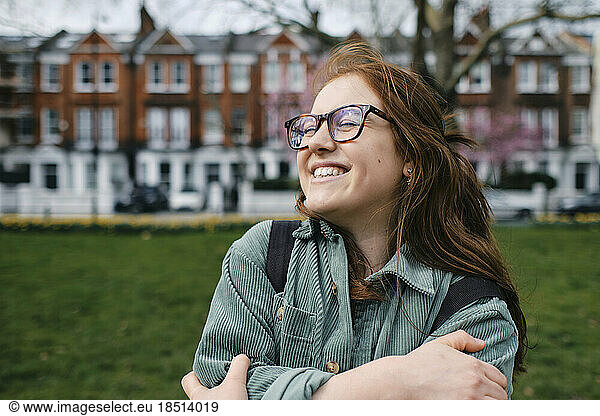 Cheerful young woman wearing eyeglasses hugging self