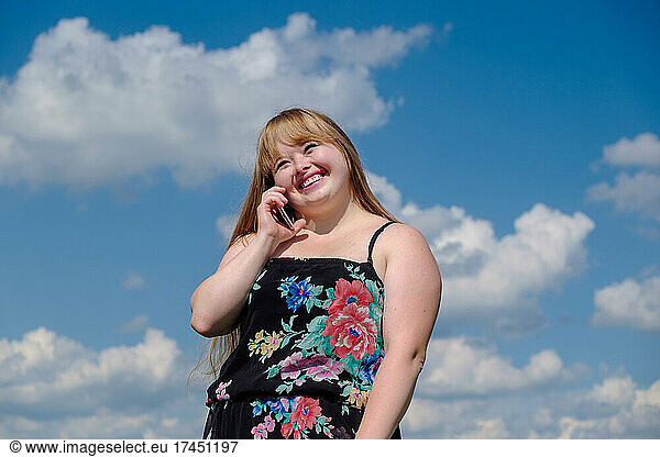 cheerful young woman with down syndrome talking on a mobile phone