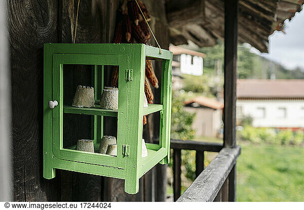 Cheese in green cabinet hanging at balcony