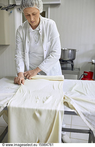 Cheese production female worker rolling cheese rolled layered cheese