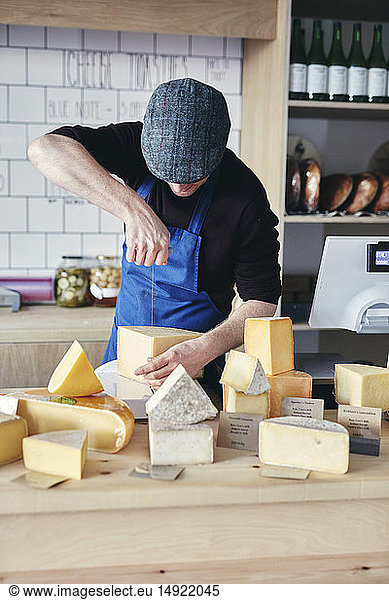 Cheesemonger cutting cheese using cheese wire