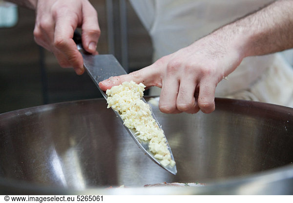 Chef adding diced onions to bowl