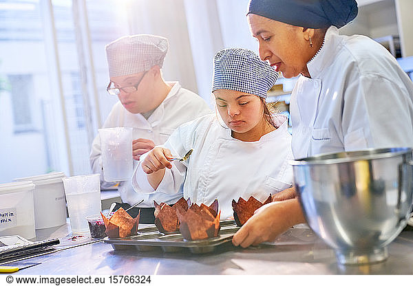 Chef and young woman with Down Syndrome baking muffins