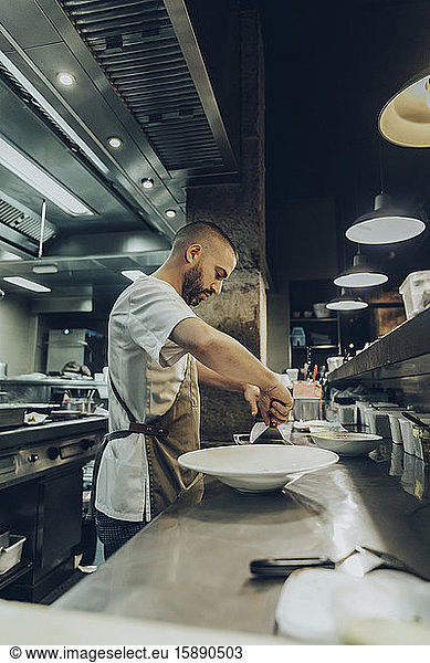 Chef arranging food on plate before serving in restaurant