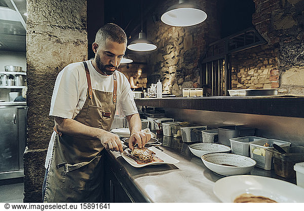 Chef arranging food on plate before serving in restaurant