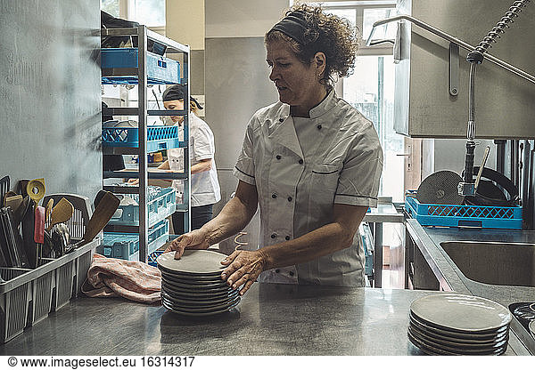 Chef arranging plates on kitchen counter in restaurant