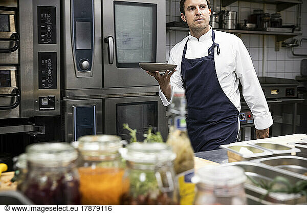 Chef carrying plate while working at kitchen of restaurant