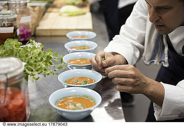 Chef garnishing soup at kitchen counter in restaurant