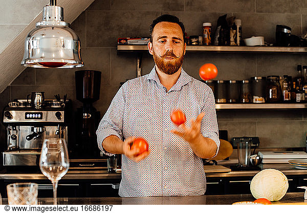 Chef juggling tomatoes at restaurant kitchen