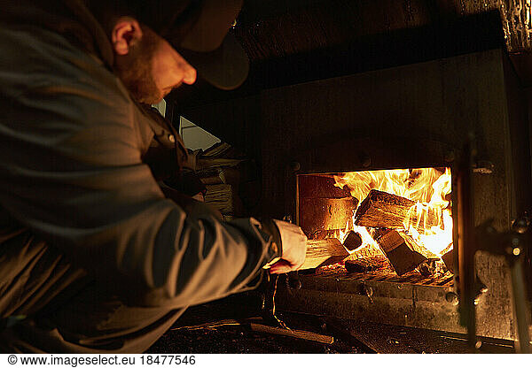 Chef putting firewood in barbecue grill