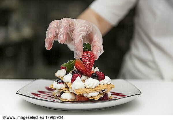 chef putting strawberry dessert