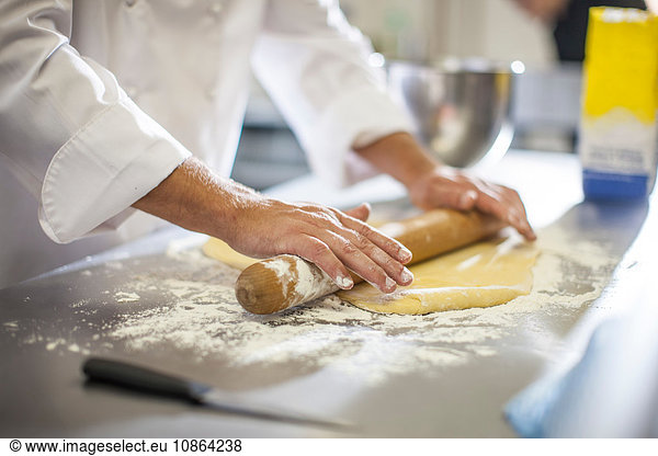 Chef rolling out dough on table