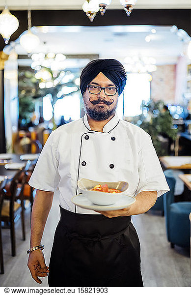 Chef serving INdian dish in his restaurant